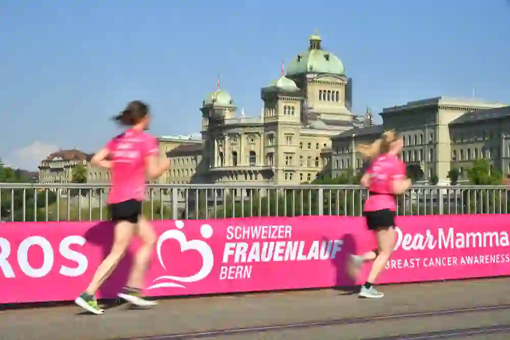 The photo shows a group of runners taking part in a women's race. They are wearing race numbers and running against a backdrop of colourful balloons.
