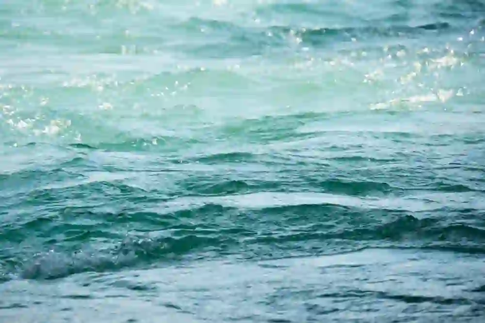 L'immagine mostra la vivace trama dell'acqua dell'Aare in primo piano, turchese e spumeggiante, catturata in un momento di tranquillo dinamismo. La luce del sole danza sulle onde, creando uno spettacolo scintillante che immerge lo spettatore nell'atmosfera pura e fresca di questo gioiello fluente di Berna.