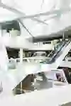 The picture shows the interior of a modern shopping centre with a futuristic design. The white, geometric structures and the bright, open spaces convey a feeling of spaciousness and modernity. The atmosphere is lively and inviting.