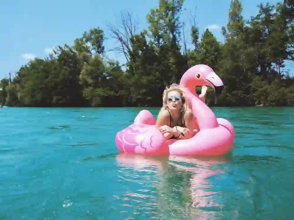 Auf diesem lebensfrohen Bild treibt eine junge Frau auf einer rosa Flamingo-Luftmatratze sanft auf dem türkisfarbenen Wasser der Aare. Mit Sonnenbrille und umgeben von der natürlichen Flusslandschaft, verkörpert sie die sorgenfreie Stimmung eines sonnigen Sommertages.
