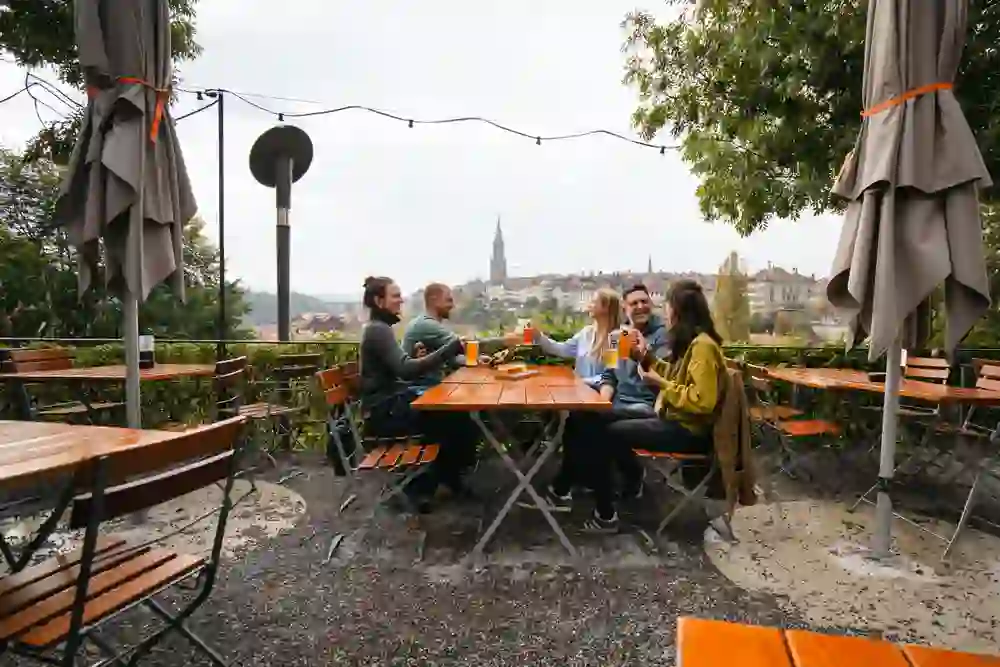 La photo montre un groupe joyeux dans l'ancien dépôt de tram, assis dehors, riant et dégustant des boissons.