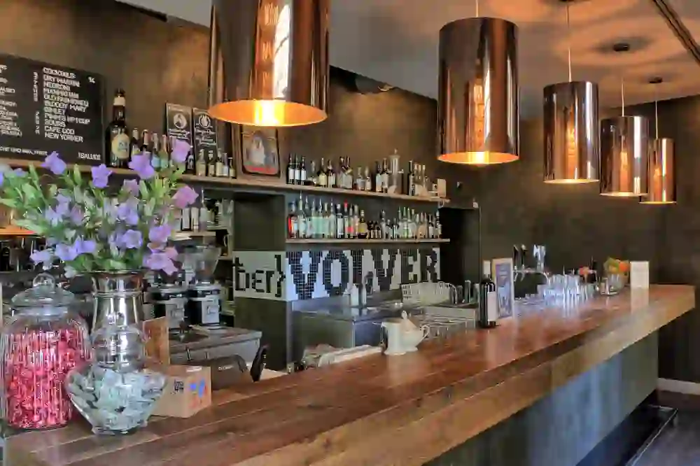 Das Bild zeigt eine einladende Bar mit warmem Licht und Blumen, was eine gemütliche und freundliche Atmosphäre schafft.