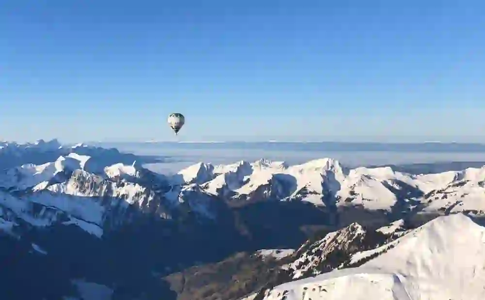 A hot-air balloon floats above snow-covered peaks, surrounded by clear winter air and endless expanses. The mountains glow in the sunlight - a quiet, majestic moment full of freedom and awe.