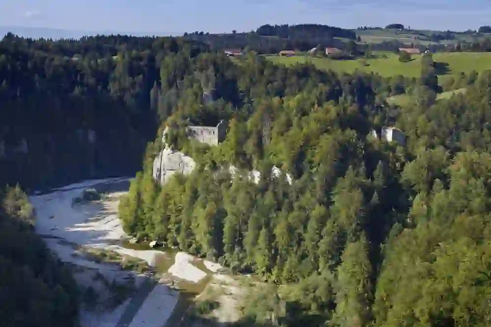 Eine Drohnenansicht zeigt die malerische Schwarzwasserschlucht in Bern, umrahmt von satten Wäldern. Die Ruine einer alten Festung thront über dem Tal und fügt der natürlichen Schönheit einen Hauch von Geschichte hinzu.