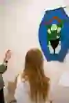 Three visitors stand in front of a colourful work of art in the Museum Cerny in Bern. An older lady raises her hand in explanation, while the two younger women listen attentively. The interest and appreciation for the art are clearly recognisable in their faces and gestures.