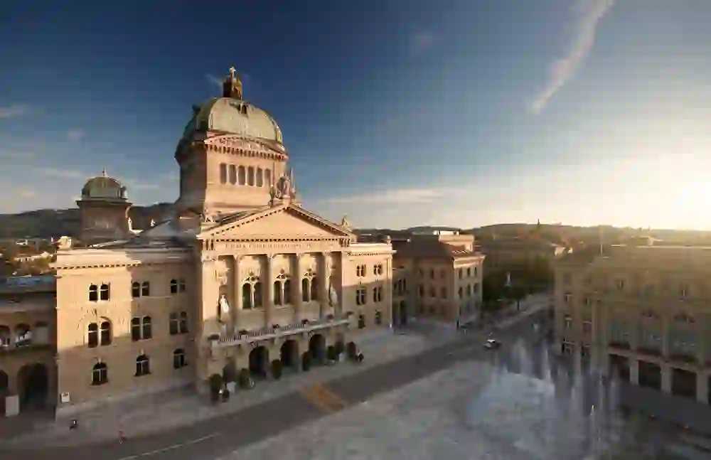 The Federal Palace in Bern is illuminated by the morning sun, giving the magnificent building and its tranquil surroundings a peaceful, hopeful atmosphere.