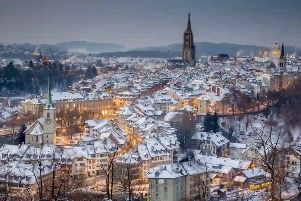 In der blauen Stunde hüllt sich Bern in ein mystisches Licht, während die Schneedecke die Stadt in Stille taucht und das Münster stolz in den Nachthimmel ragt, eine Szene von stiller Pracht.