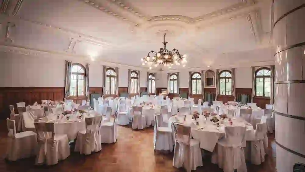 Nella sala Belle Epoque del Romantik Hotel Bären Dürrenroth, eleganti lampadari e tavoli imbanditi a festa creano un ambiente ricco di splendore e tradizione.