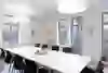 A bright, inviting seminar room in Gurten Park, equipped with a large table, comfortable chairs and modern presentation technology, offers a clear view of the surrounding nature and promotes a productive atmosphere.