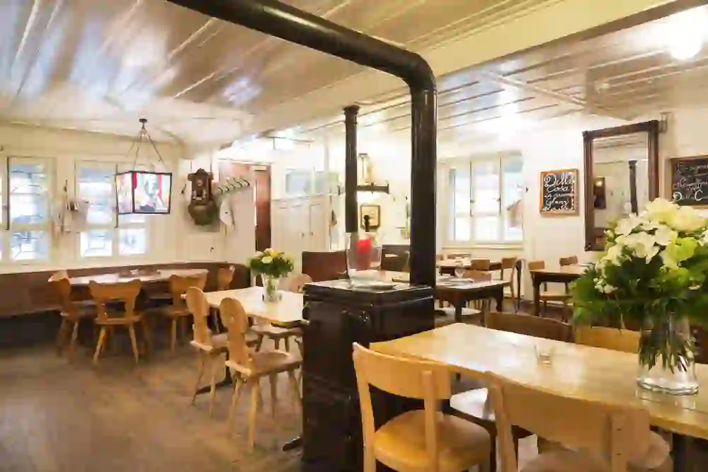 The picture shows the cosy interior of the Della Casa restaurant with a warm, inviting atmosphere, enhanced by natural wood, lively flower arrangements and nostalgic decorations.