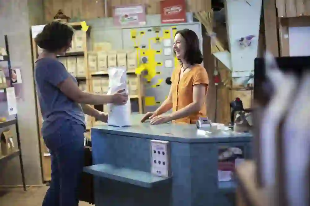 Das Foto zeigt zwei Personen in einem freundlichen und anscheinend entspannten Austausch über einen Ladentresen hinweg.