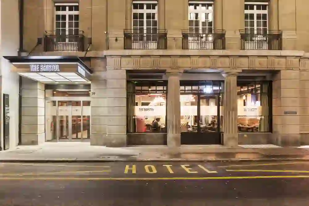 The picture shows the illuminated façade of "The Bristol" hotel at night, which radiates an inviting and elegant atmosphere.