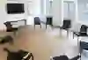 Une salle de séminaire sobre avec un mobilier et un équipement technique modernes pour une présentation ou une réunion. L'intérieur clair et le parquet créent une atmosphère claire et concentrée.
