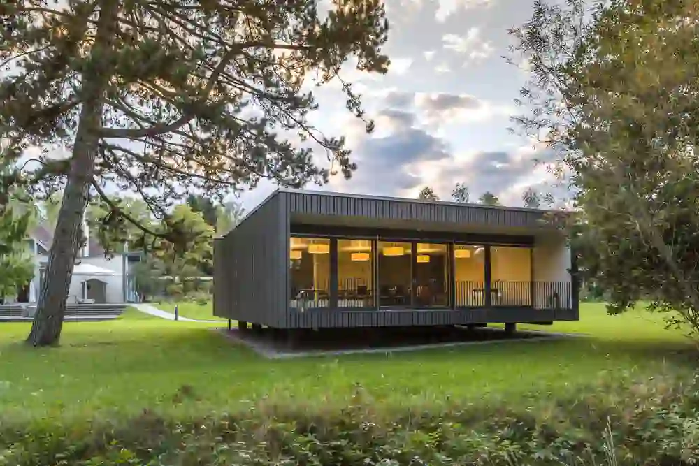 Le pavillon du château de Hünigen, embrassé par la douceur du vert et la lumière du soir, promet un refuge paisible pour les moments de recueillement et les réunions.
