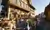 The picture shows a traditional Alpine procession in Sumiswald: festively decorated cows and people in traditional costume parade through a village with richly decorated houses. The atmosphere is lively and festive - a celebration of customs and community.