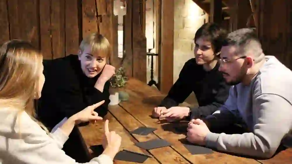 In der warmen Atmosphäre des Regionalmuseums Chüechlihus in Langnau vertieft sich eine Gruppe junger Erwachsener in eine interaktive Aufgabe, umgeben von uriger Holzarchitektur und im Licht der Gemeinschaft.