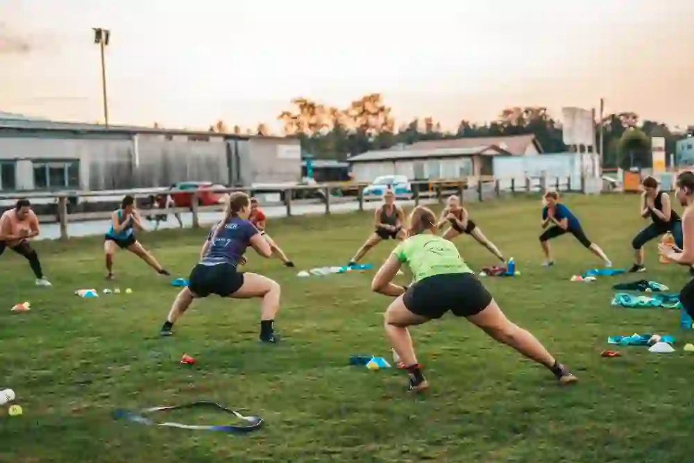 Das Bild zeigt ein motivierendes Outdoor-Sporttraining in Bern. Eine Gruppe trainiert gemeinsam auf einer Wiese im Abendlicht. Die Atmosphäre ist energiegeladen und inspirierend – Freude an Bewegung, Teamgeist und frische Luft schaffen ein positives Gemeinschaftsgefühl.
