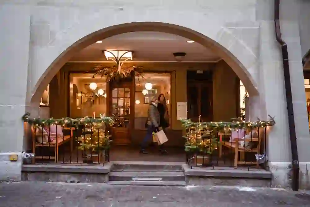 Das Bild zeigt zwei Personen die unter den Lauben der Berner Altstadt bei festlicher Beleuchtung shoppen