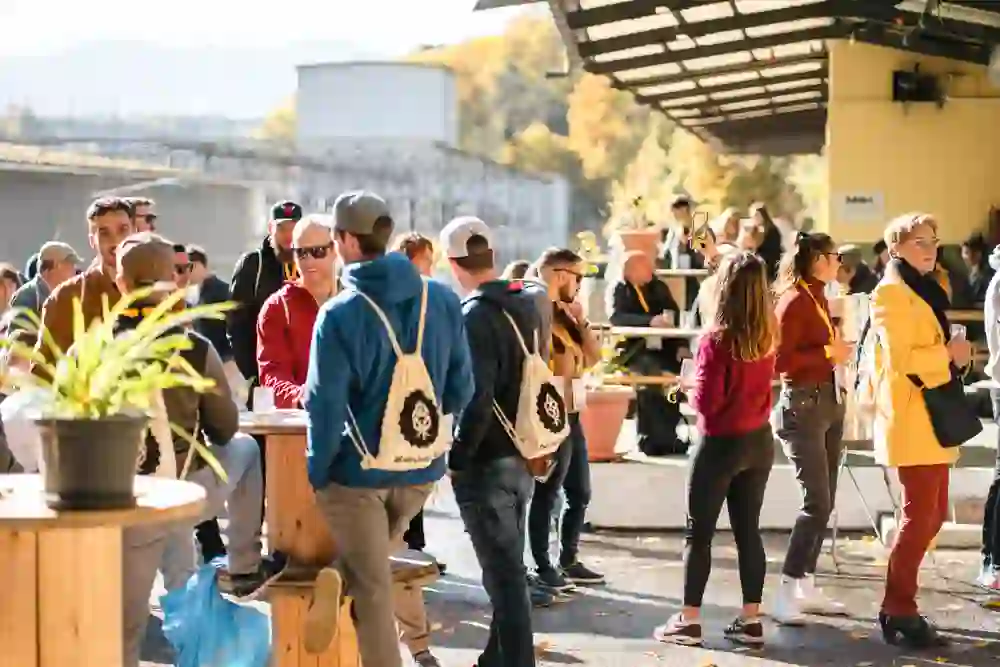 Eine lebhafte Menge genießt sonniges Wetter auf einem Brauereifest. Die entspannte und fröhliche Stimmung wird durch die warmen Sonnenstrahlen und die gemütlichen Gespräche unter Freunden noch verstärkt.