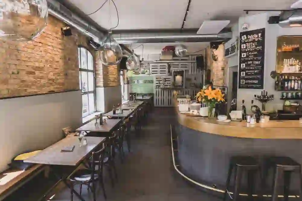 L'image montre l'intérieur plein d'ambiance du local "Barbiere", avec une atmosphère sereine et accueillante, caractérisée par des lumières chaudes et un mur de briques rustiques.