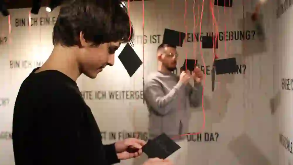 Die Ausstellung im Regionalmuseum Chüechlihus in Langnau weckt Neugier, während Besucher interaktiv mit schwebenden Gedankenfetzen verbunden sind, eine spielerische Auseinandersetzung mit der Umgebung und dem Selbst.