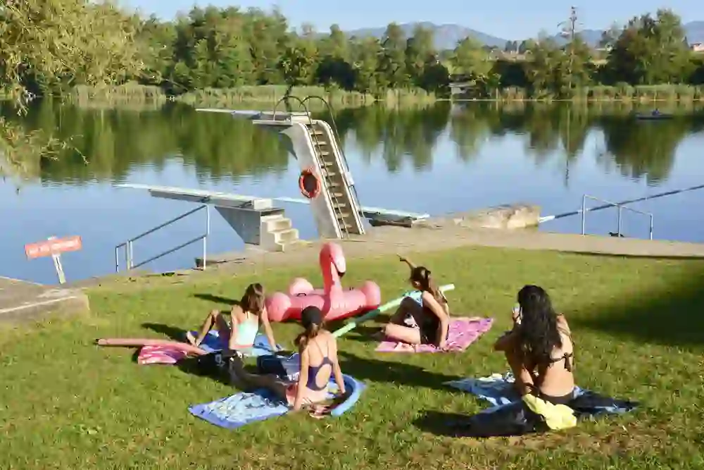Eine entspannte Gruppe geniesst einen sonnigen Tag am Ufer des Burgäschisees, begleitet von aufblasbaren Schwimmringen, bereit für eine Abkühlung in der ruhigen Umgebung.