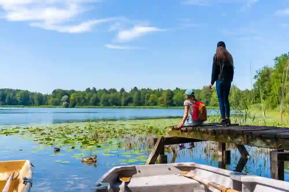 Deux personnes se tiennent sur un ponton en bois au bord du paisible lac de Burgäschi, entourées de la nature paisible et de canards sur l'eau qui profitent de la scène silencieuse.