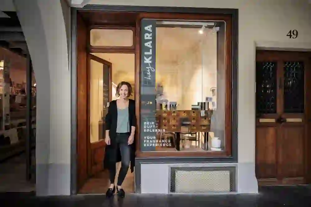 Das Bild zeigt eine stilvolle Auswahl an Parfüm-Verpackungen und einer Glasflasche mit dem Label "hey KLARA". Die Verpackungen sind elegant in Schwarz gehalten und mit farbigen Banderolen versehen, auf denen liebevoll gestaltete Botschaften wie „Flowers for you“ und „Because you are unique!“ stehen. Die Gestaltung ist minimalistisch und modern, vermittelt aber gleichzeitig eine persönliche Note, die sich perfekt für Geschenke eignet. Die Glasflasche und die hochwertigen Verpackungen auf einer rustikalen Holzoberfläche verstärken den Eindruck von Eleganz und Exklusivität. Diese Präsentation lädt dazu ein, die Düfte als besondere und persönliche Geschenke zu erleben.