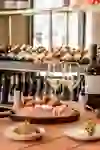 The picture shows a table laid with a selection of Italian antipasti, accompanied by a glass of white wine and a bottle of wine. Wine bottles can be seen in the background, suggesting a wine bar. The atmosphere is inviting and cosy, perfect for an enjoyable meal in relaxed surroundings.