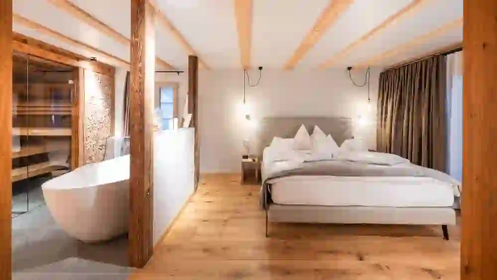 The picture shows a cosy hotel room in the Kemmeriboden bathroom, which is designed with natural materials such as wood. The open bathtub gives the room a luxurious and relaxing atmosphere.