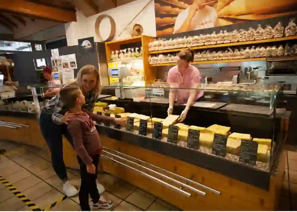 In the shop of the Emmental show dairy, the saleswoman's warm smile creates a welcoming atmosphere, while a child looks at the cheese selection with astonished eyes.