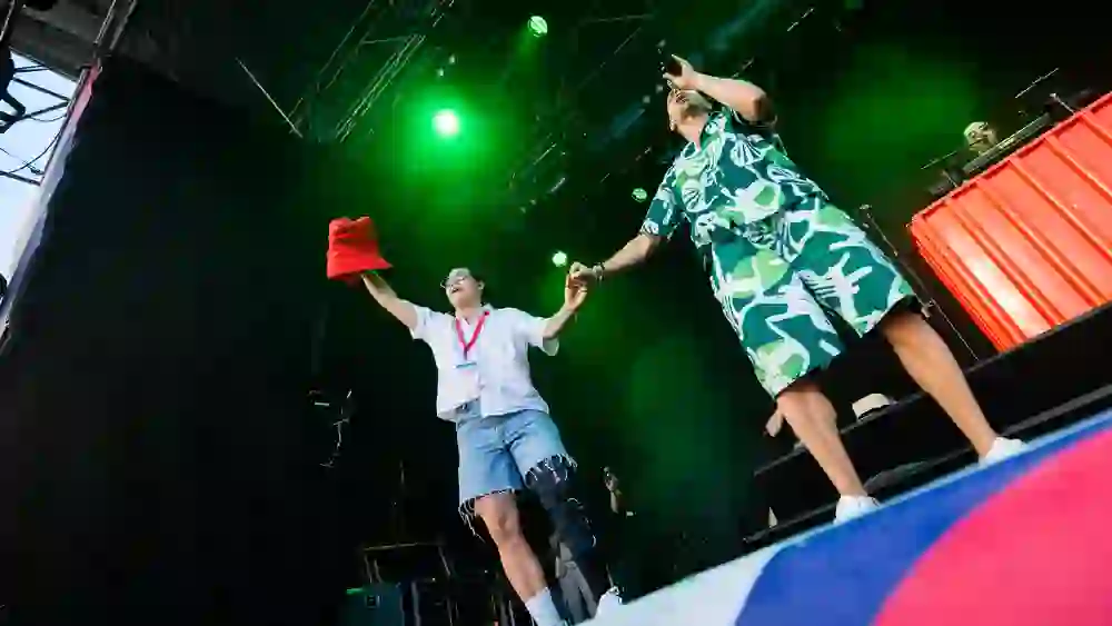 La photo montre le chanteur Dodo et la joueuse de football Ramona Bachmann ensemble sur scène pendant le concert de Dodo dans le cadre de l'UEFA Women's Euro 2025.