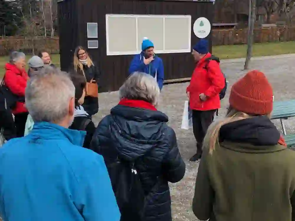 Il gruppo ascolta due oratori; uno gesticola con entusiasmo. Il pubblico sembra interessato e concentrato, nonostante il clima più freddo.