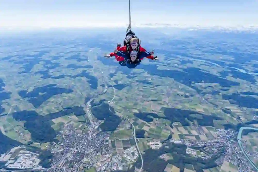 Hoch über der atemberaubenden Landschaft schweben Tandemspringer von Swissboogie im freien Fall, umgeben von einem Gefühl grenzenloser Freiheit und Abenteuer.