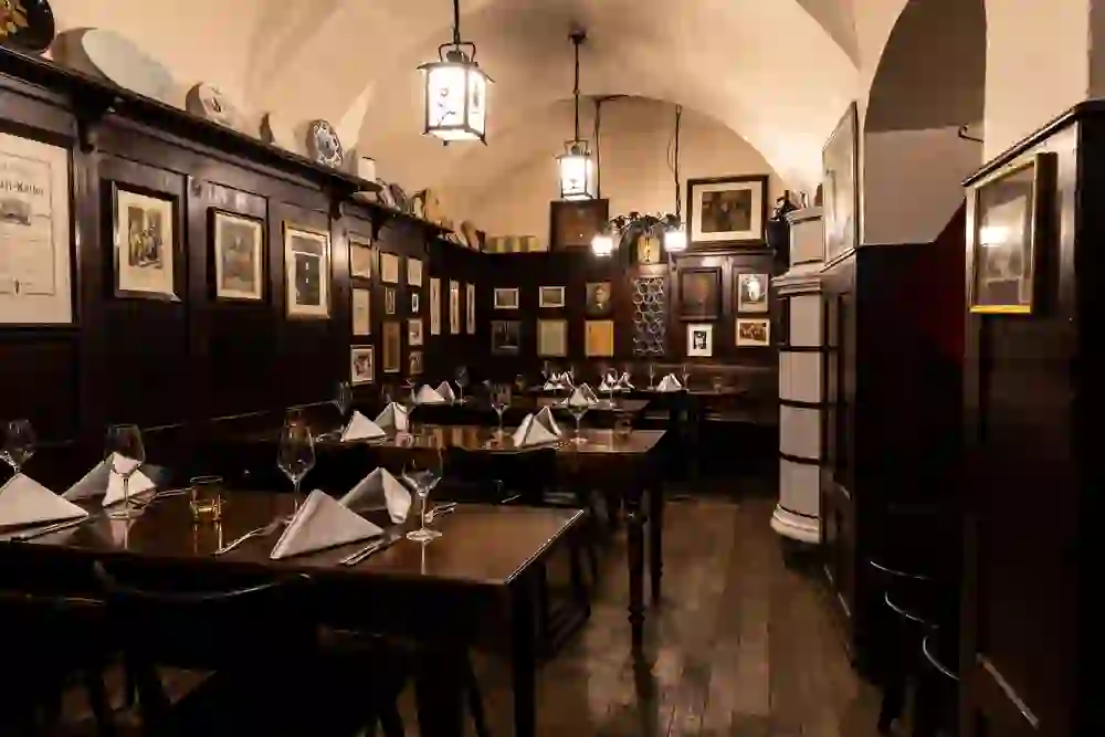 The photo presents the historic charm of the wine bar in the Klötzlikeller in Bern, with subdued lighting that creates an intimate and traditional atmosphere, emphasised by dark wood and antique decorations.