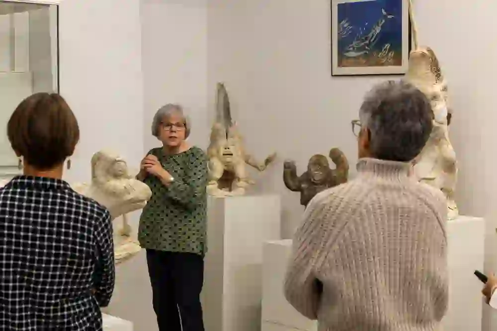 A group of visitors listen to a guide at the Museum Cerny in Bern as she talks passionately about the sculptures on display. Her gestures and the attentive gaze of the listeners indicate an exchange of knowledge and the deep connection that people can form with art.