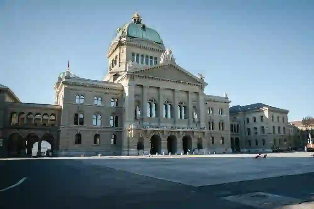 Das Bundeshaus ragt majestätisch über den fast leeren Bundesplatz. Im klaren Morgenlicht wirkt die Szenerie ruhig und würdevoll, als würde die Stadt einen stillen Atemzug voller Bedeutung nehmen.