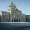 Le Palais fédéral se dresse majestueusement au-dessus de la Place fédérale presque vide. Dans la lumière claire du matin, la scène semble calme et digne, comme si la ville prenait une respiration silencieuse pleine de sens.
