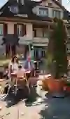 A family sits outside a charming house in a café, eating and laughing together. Sunshine and green plants create a light, cheerful atmosphere full of relaxation and family togetherness.