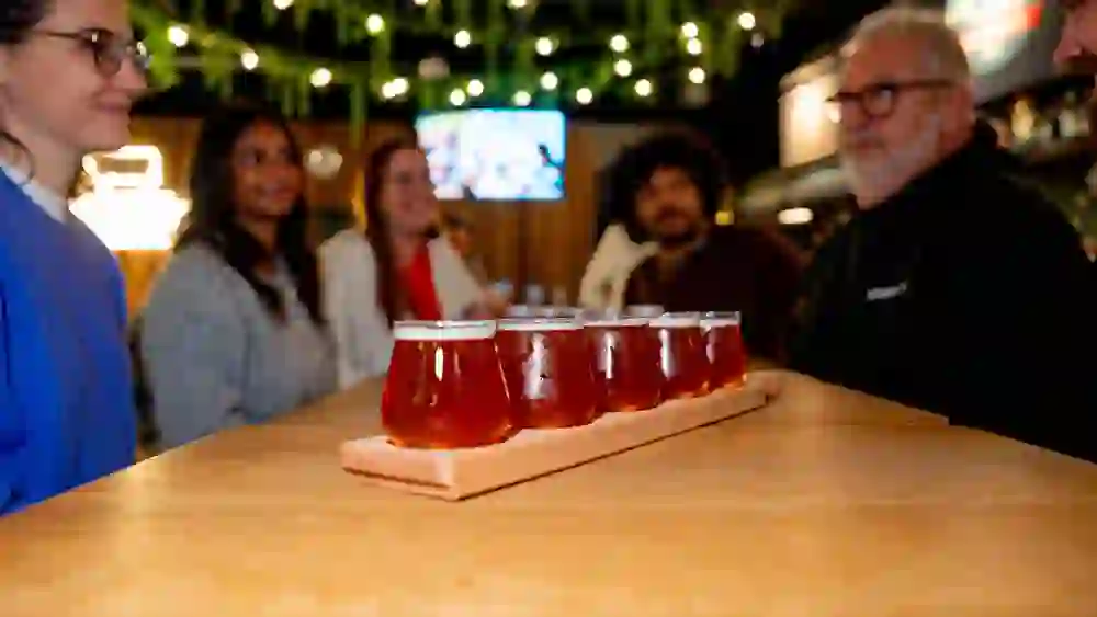 The picture shows beer glasses with people in the background as part of the city tour Pub Biertour