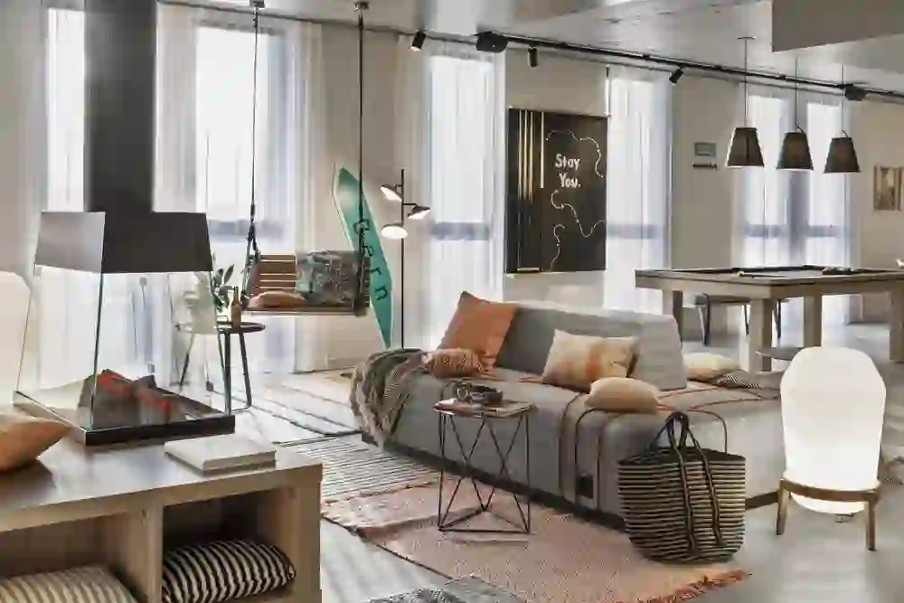 Das Bild zeigt einen einladenden Gemeinschaftsraum im Stay Kooook Wankdorf mit bequemen Sitzgelegenheiten und warmen Farbakzenten, der eine entspannte und heimelige Atmosphäre ausstrahlt.