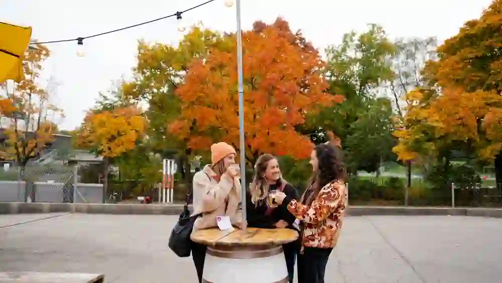 The picture shows three women at a round wooden table on a brewery walk in Bern