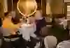 Guests are seated at a laid table in the Kornhauskeller in Bern and raise their wine glasses in a toast. The historic interior and warm lighting create a cosy and convivial atmosphere.