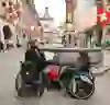 L'image montre des personnes en fauteuil roulant explorant le centre-ville animé, avec son architecture historique et ses drapeaux suisses. L'atmosphère est vivante et inclusive, avec un sentiment de communauté et d'accessibilité.