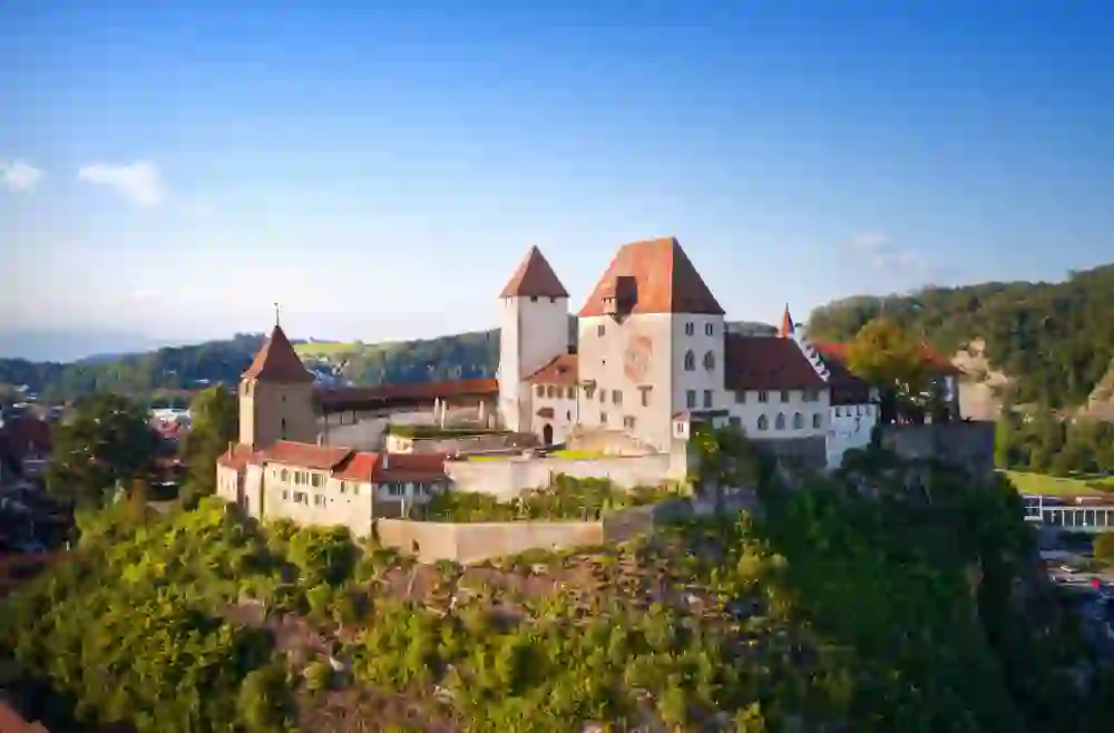 Schloss Burgdorf thront majestätisch auf einem Felsvorsprung, umgeben von sattgrüner Natur und einem klaren Himmel, was eine Atmosphäre von historischer Bedeutung und zeitloser Schönheit vermittelt.