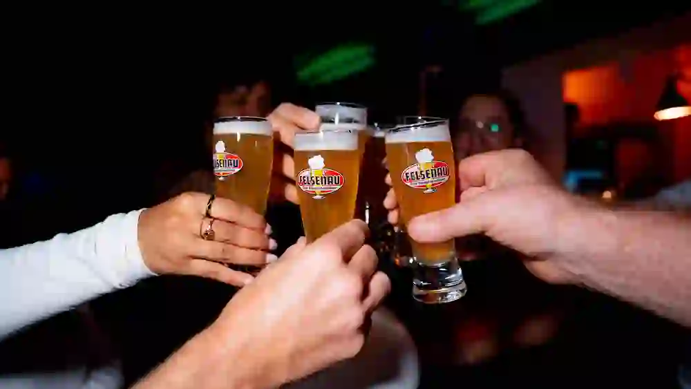The picture shows a close-up of people toasting with beer as part of a city tour on the subject of a pub beer tour