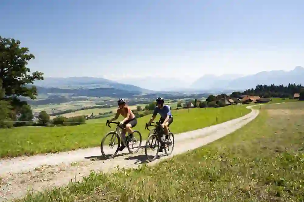 L'immagine mostra tre persone durante un tour su ghiaia, con il bellissimo Oberland Bernese e le Alpi sullo sfondo.