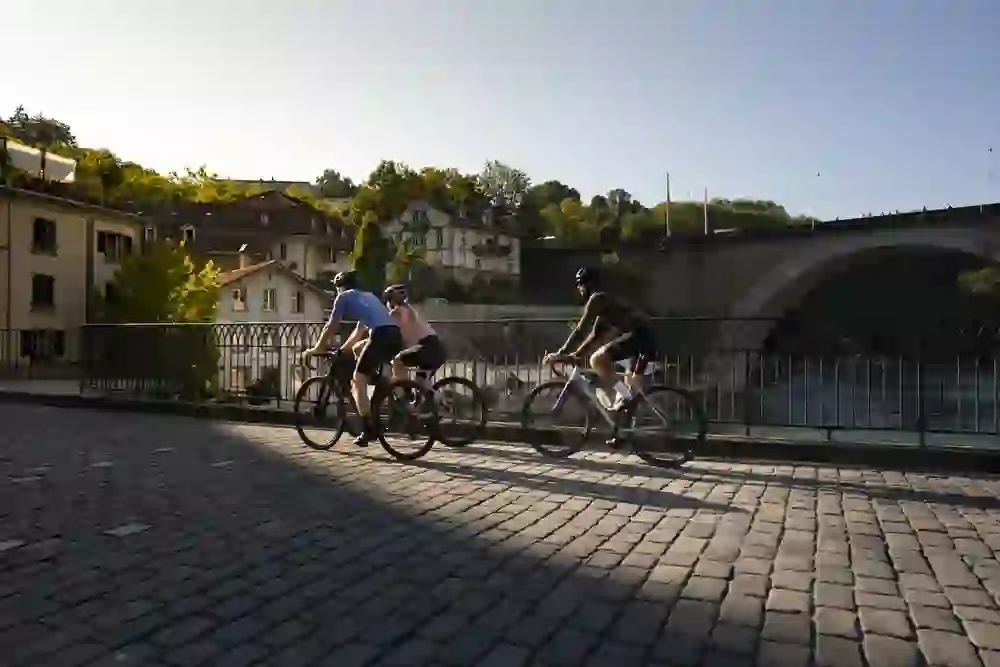 L'immagine mostra tre persone su una bici da corsa nella città di Berna in una mattina d'estate o d'autunno.