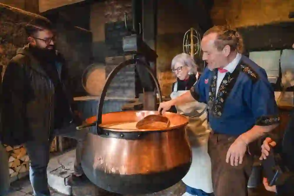 In a cosy atmosphere, a visitor watches in fascination as traditional cheese is made by hand in a large copper cauldron, while experienced cheesemakers in traditional costume demonstrate their craft.