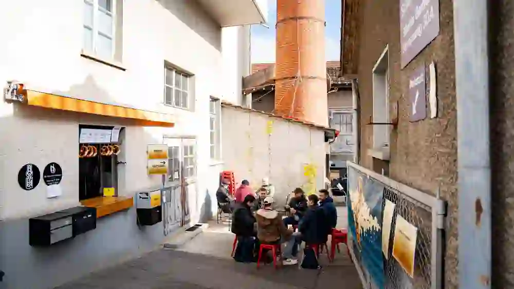The picture shows people sitting at a table in a cosy atmosphere on the Bern brewery ice walk